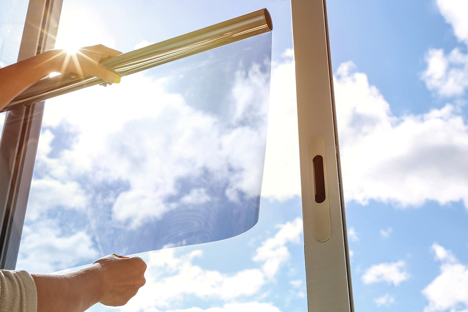 person holding up window film next to window