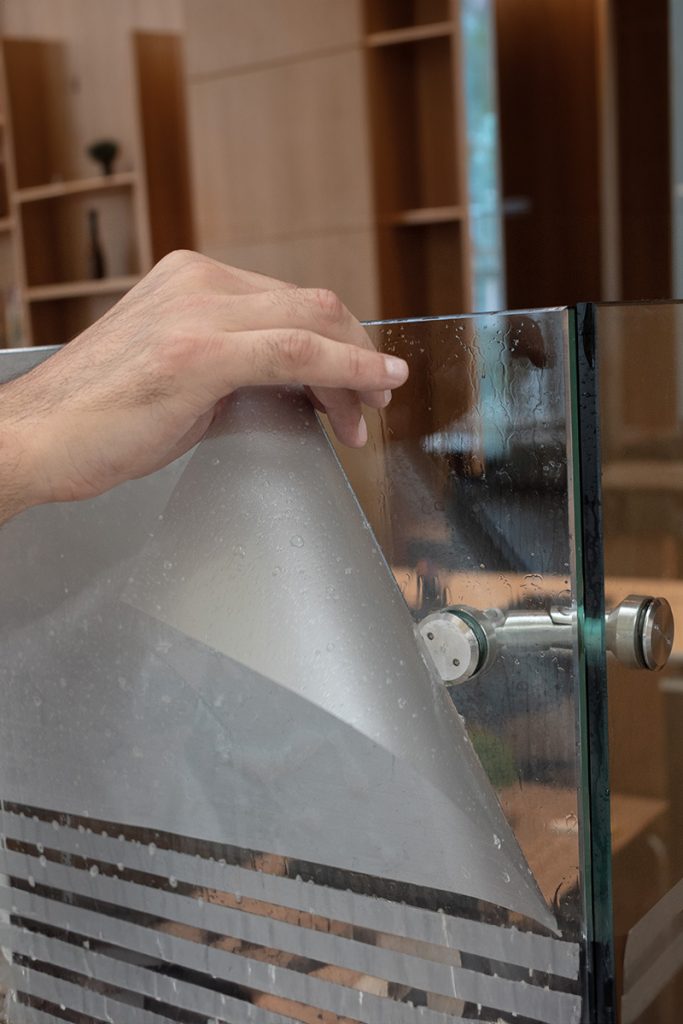 person applying frosted glass window film